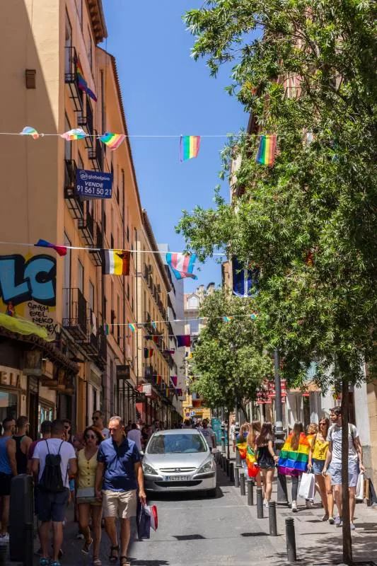 A crowded street in Chueca, decorated with LGBT+ flags
