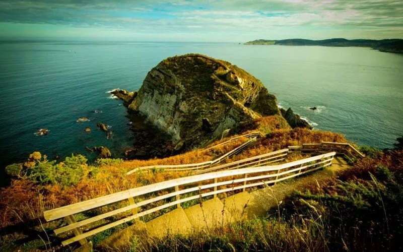 A rock formation next to the sea, viewed from a narrow staircase that goues down