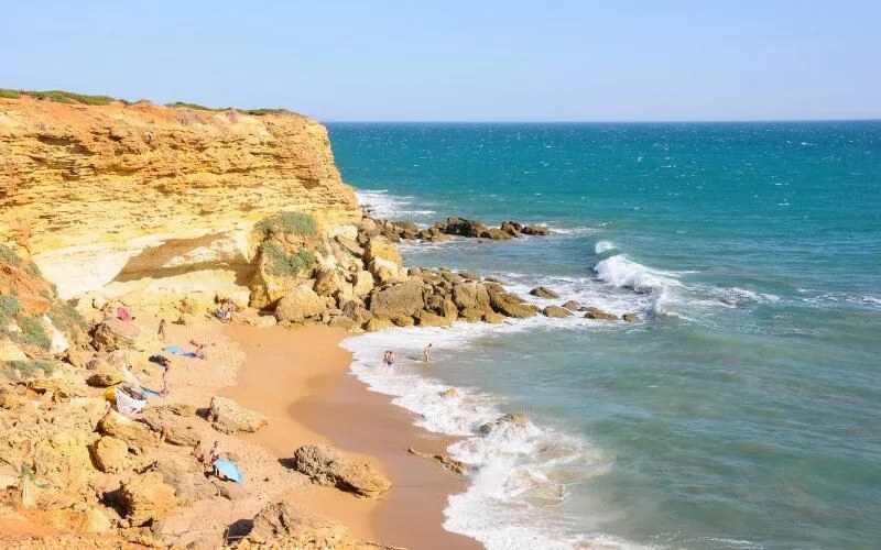 A beach with golden sand and rocks