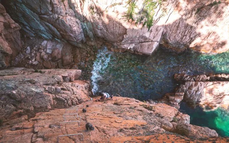 Stairs going down a rock face with water below 