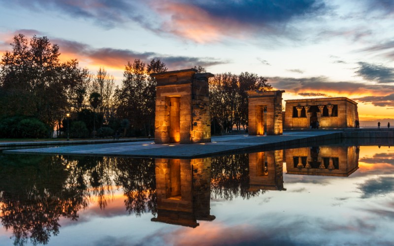 An Egyptian temple surrounded by water under the sunset