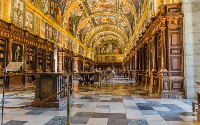 A richly decorated gallery with bookshelves and paintings