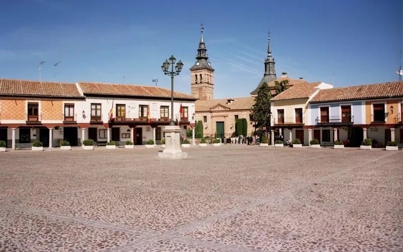 A cobbled square and a church with a tower in front