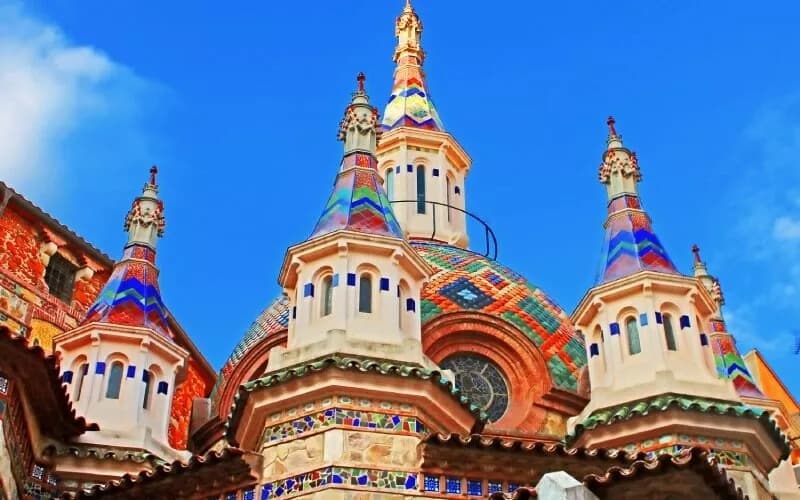 A colourful modernist building with towers and mosaics