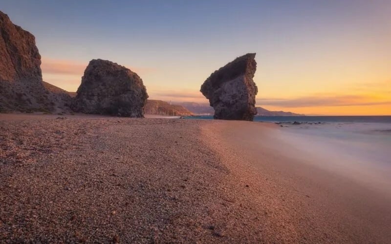 A beach of pebbles and rocks in the background