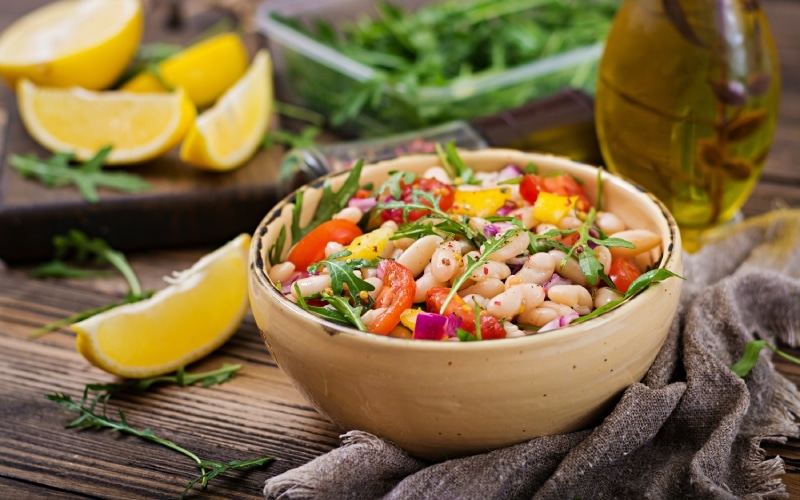 A bowl with salad on a table with lemons and olive oil 