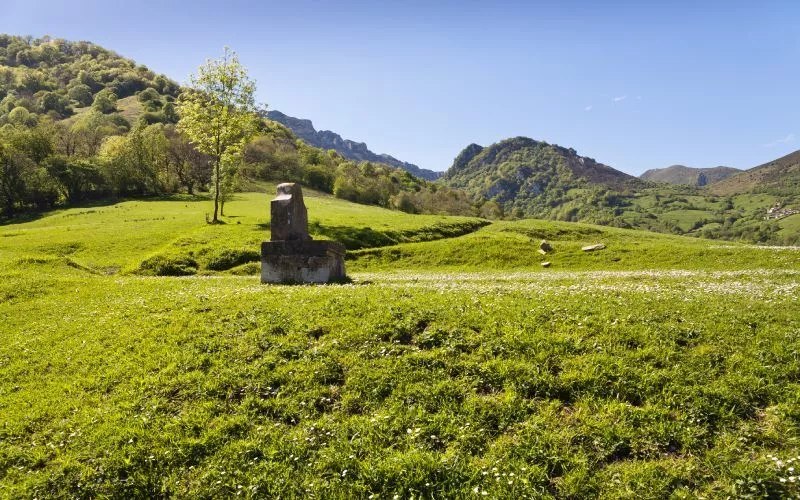 A stone fountain on a green valley