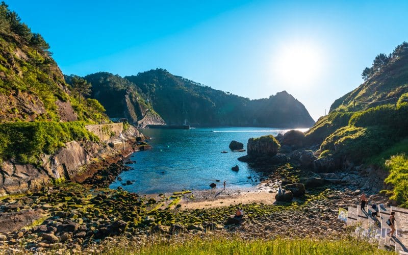 A small blue beach between green hills under the sun