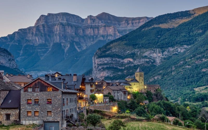 A village with dark tiles and stone houses under breathtaking mountains