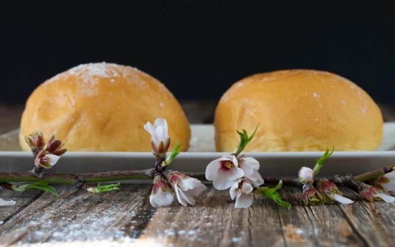 Two round pieces of pastry or potato cocas on a plate with flower petals