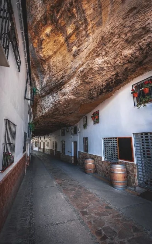A street of white houses under a rock