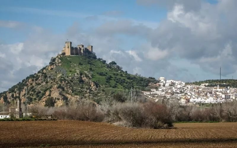 A castle on a cliff and a town with white houses