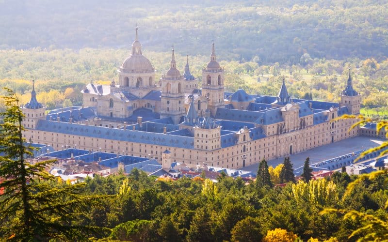 A distant view of a monastery and some trees in front