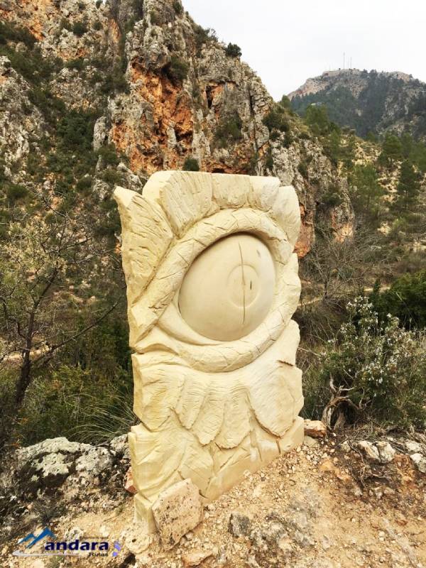 The sculpture of an eye surrounded by nature