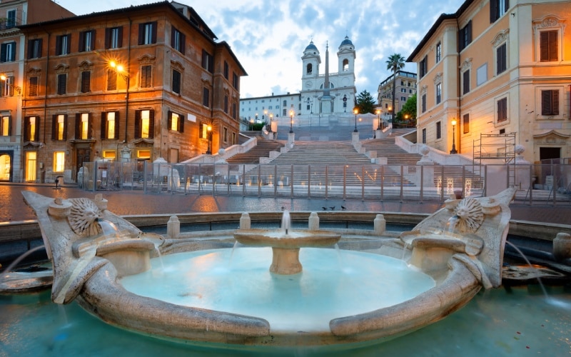 A fountain and a staircase in the middle of the Spanish square, with a white church on top